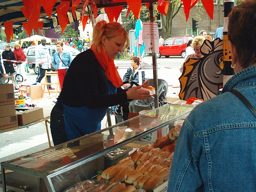 Middenweg 52 - 2005 De viskraam van Braan op de Hogeweg/hoek Middenweg tijdens het Bredewegfestival op Koninginnedag 2005. In de kraam de kleindochter van de oprichter van de viswinkel.<br />.<br />//Foto: 